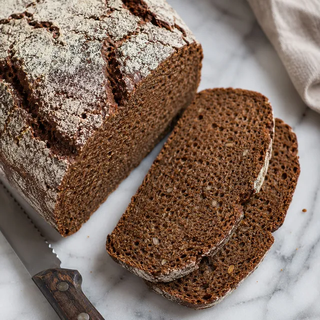 Sliced dark rye sourdough bread with caraway seeds showing a moist dense crumb