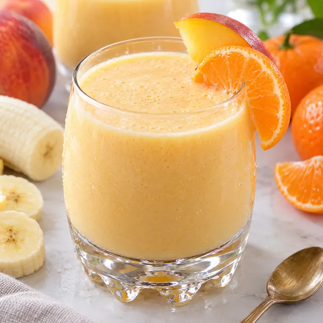 Koktajl brzoskwiniowy z bananem w szklance z plastrem brzoskwini