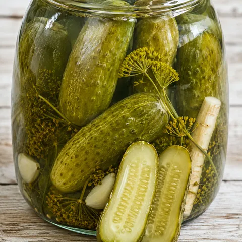 Jar of Polish fermented dill pickles with garlic and dill in cloudy brine
