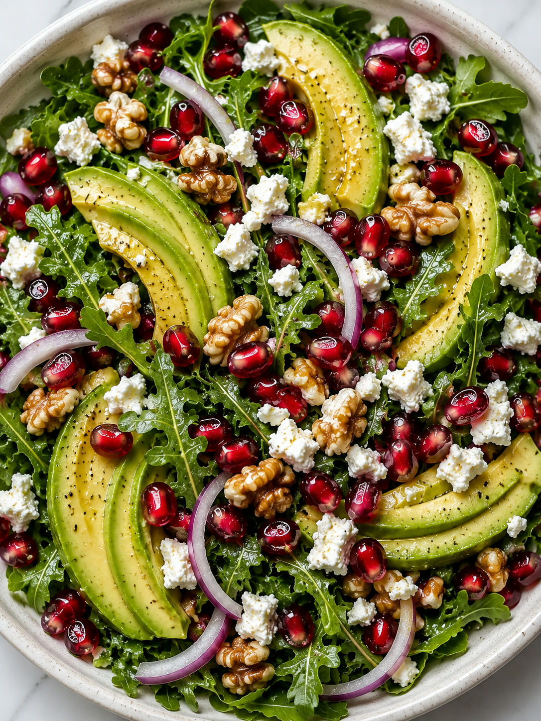 Top-down view of avocado and pomegranate salad with feta and walnuts