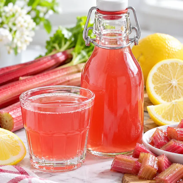 Różowy syrop z rabarbaru i cytryny w szklance i butelce